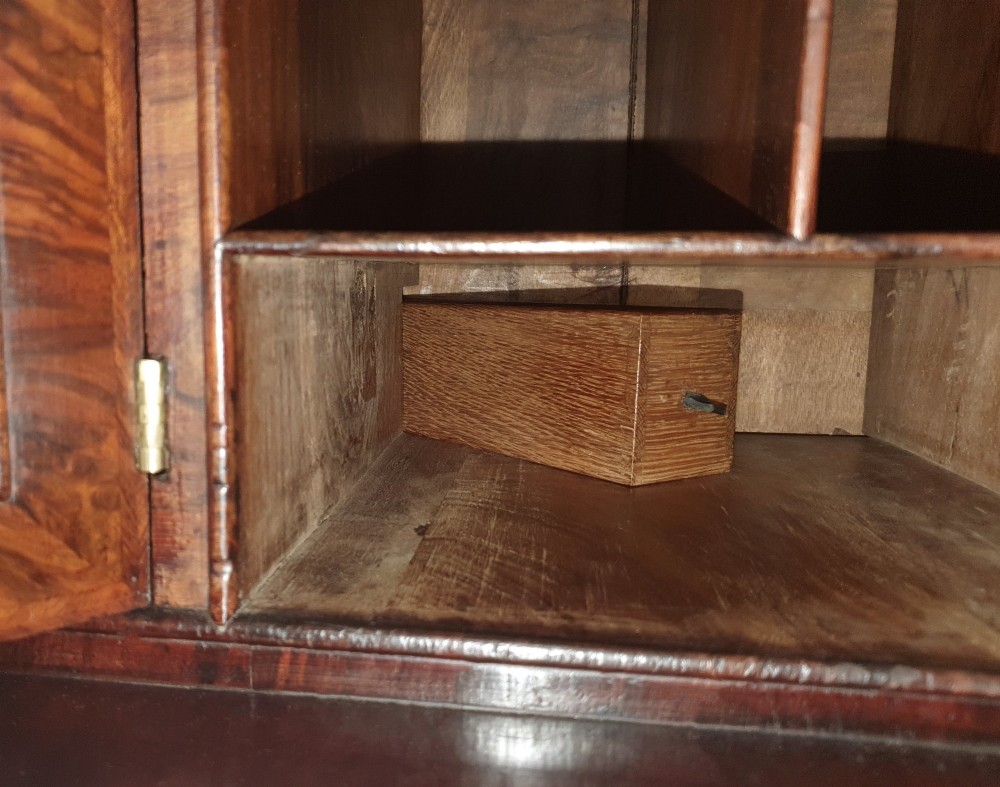 An early 18th-century Queen Anne burr walnut bureau bookcase featuring an open double-domed upper cabinet with fitted interior pigeonholes above a fall-front desk section. View X