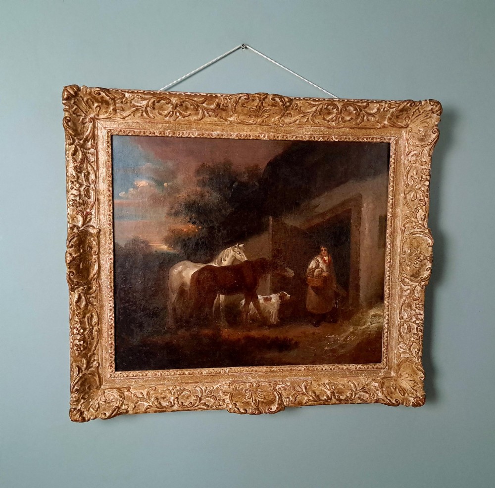 A nineteenth-century framed oil painting showing a rural farmyard scene with two horses, a dog, and a figure beside a doorway.