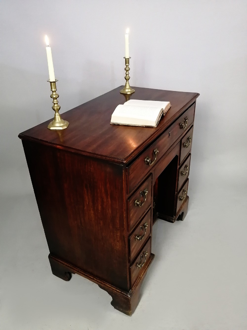 An 18th-century Georgian mahogany kneehole desk featuring multiple drawers with brass handles, bracket feet, and a central cupboard door. View III