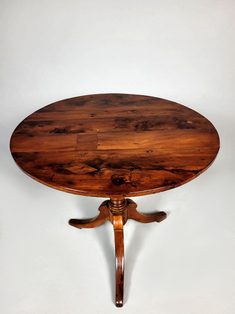 A Georgian yew wood circular tilt-top wine table featuring a turned central pedestal and a tripod base. View III