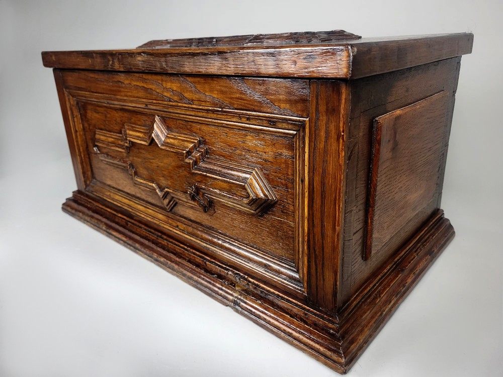 An open seventeenth-century oak safe box featuring raised geometric mouldings on the front panel and a hand-forged steel lock plate inside the lid. View III
