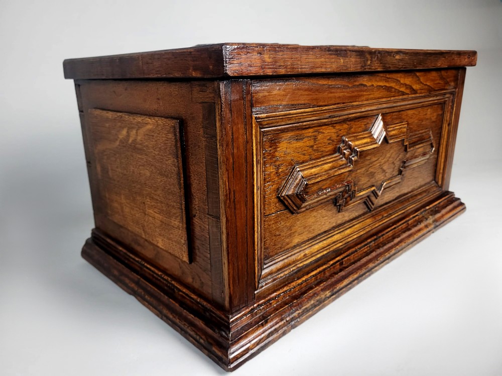 An open seventeenth-century oak safe box featuring raised geometric mouldings on the front panel and a hand-forged steel lock plate inside the lid. View IV