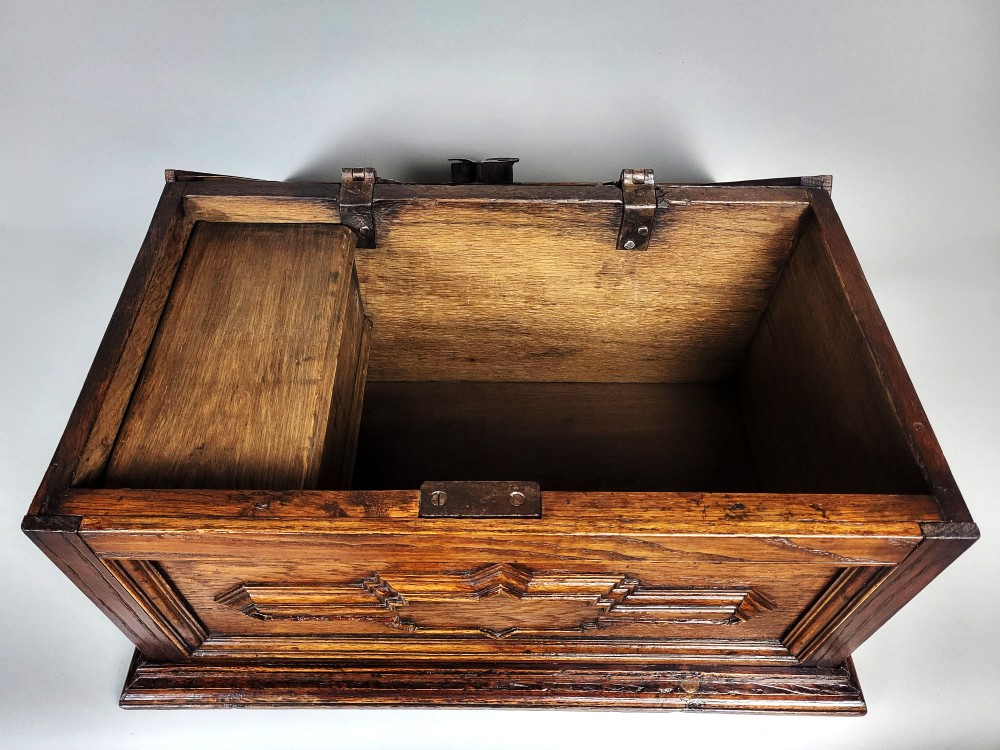An open seventeenth-century oak safe box featuring raised geometric mouldings on the front panel and a hand-forged steel lock plate inside the lid. View VII