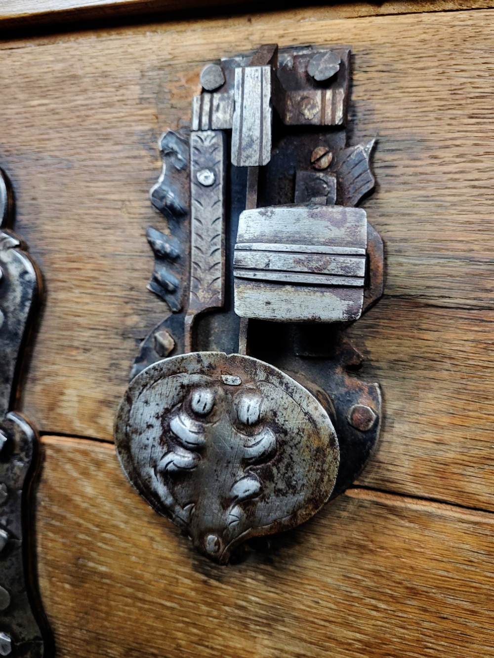 An open seventeenth-century oak safe box featuring raised geometric mouldings on the front panel and a hand-forged steel lock plate inside the lid. View VIII