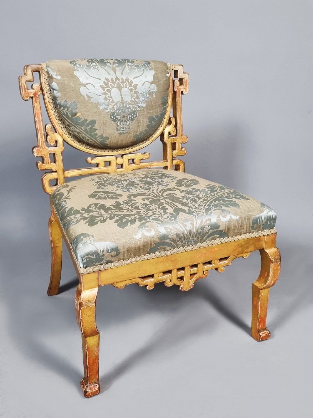 A 19th-century Chinese Chippendale style giltwood side chair featuring carved fretwork and damask upholstery.