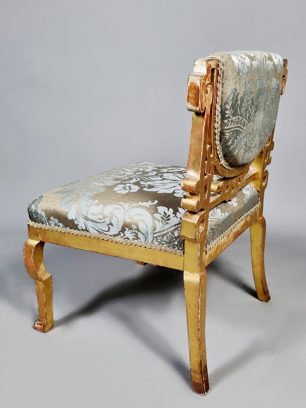 A 19th-century Chinese Chippendale style giltwood side chair featuring carved fretwork and damask upholstery. View V