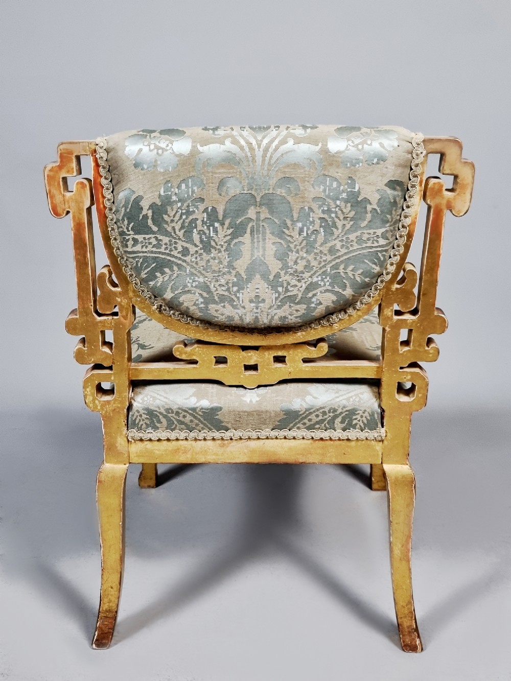 A 19th-century Chinese Chippendale style giltwood side chair featuring carved fretwork and damask upholstery. View VI