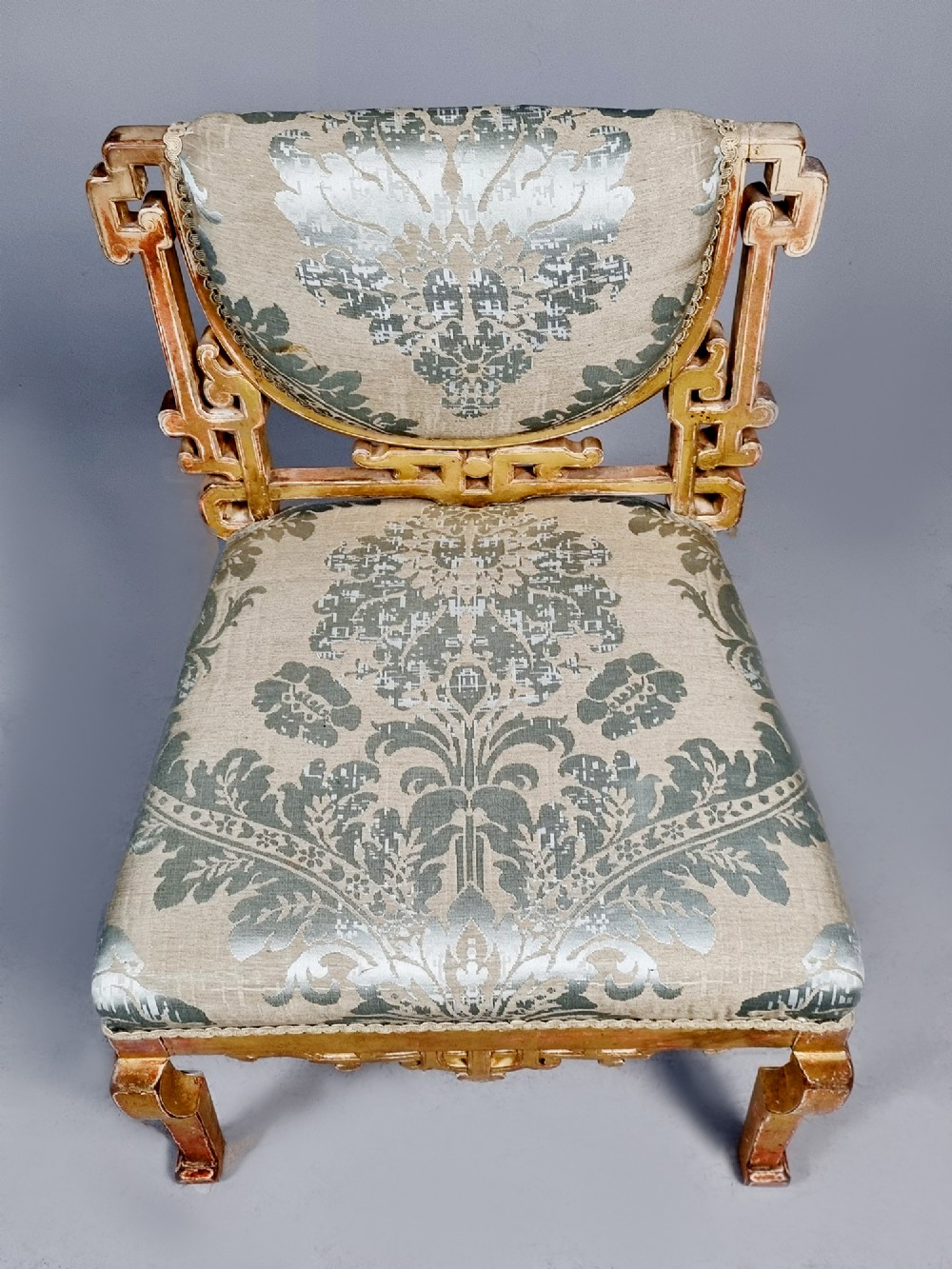 A 19th-century Chinese Chippendale style giltwood side chair featuring carved fretwork and damask upholstery. View VIII