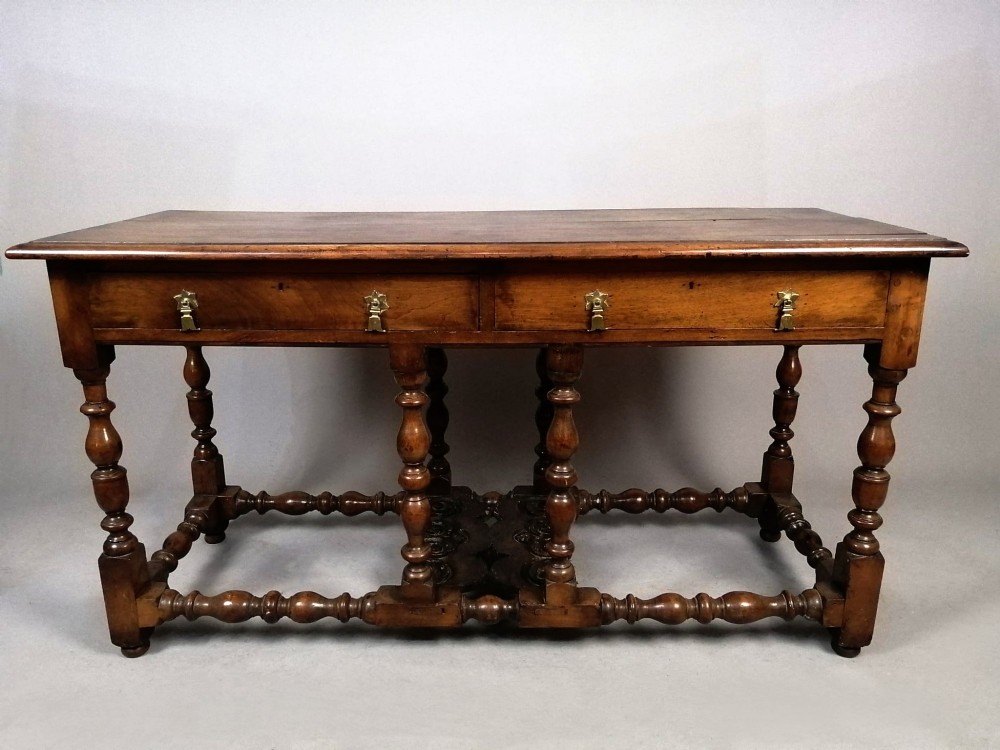 A Georgian walnut dresser sideboard featuring two frieze drawers with brass drop handles, turned legs, and low stretchers.