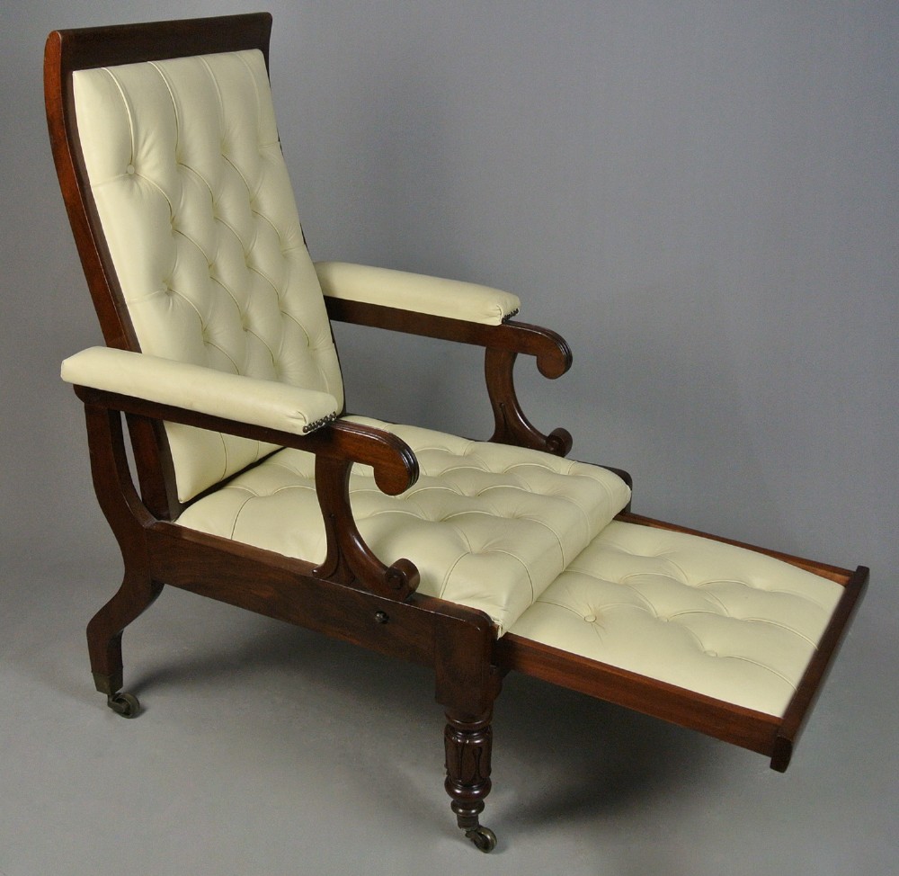 A Regency mahogany reclining armchair featuring cream button-tufted leather upholstery, scroll arms, and turned front legs on brass castors. View II