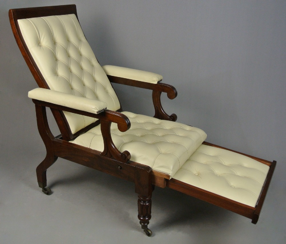 A Regency mahogany reclining armchair featuring cream button-tufted leather upholstery, scroll arms, and turned front legs on brass castors. View IV