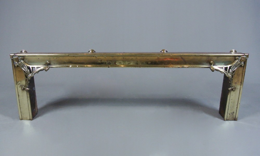 An Art Nouveau fire fender made of hammered copper with a polished brass top rail, corner mounts, and small rounded feet. View V