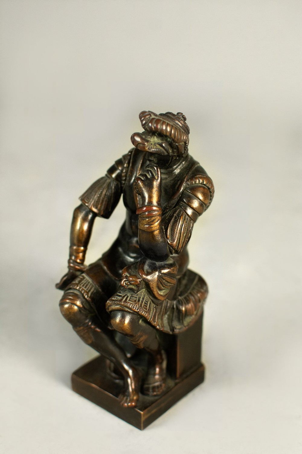 A dark patinated bronze figure depicting Lorenzo de Medici seated in a thoughtful pose on a rectangular base. View III