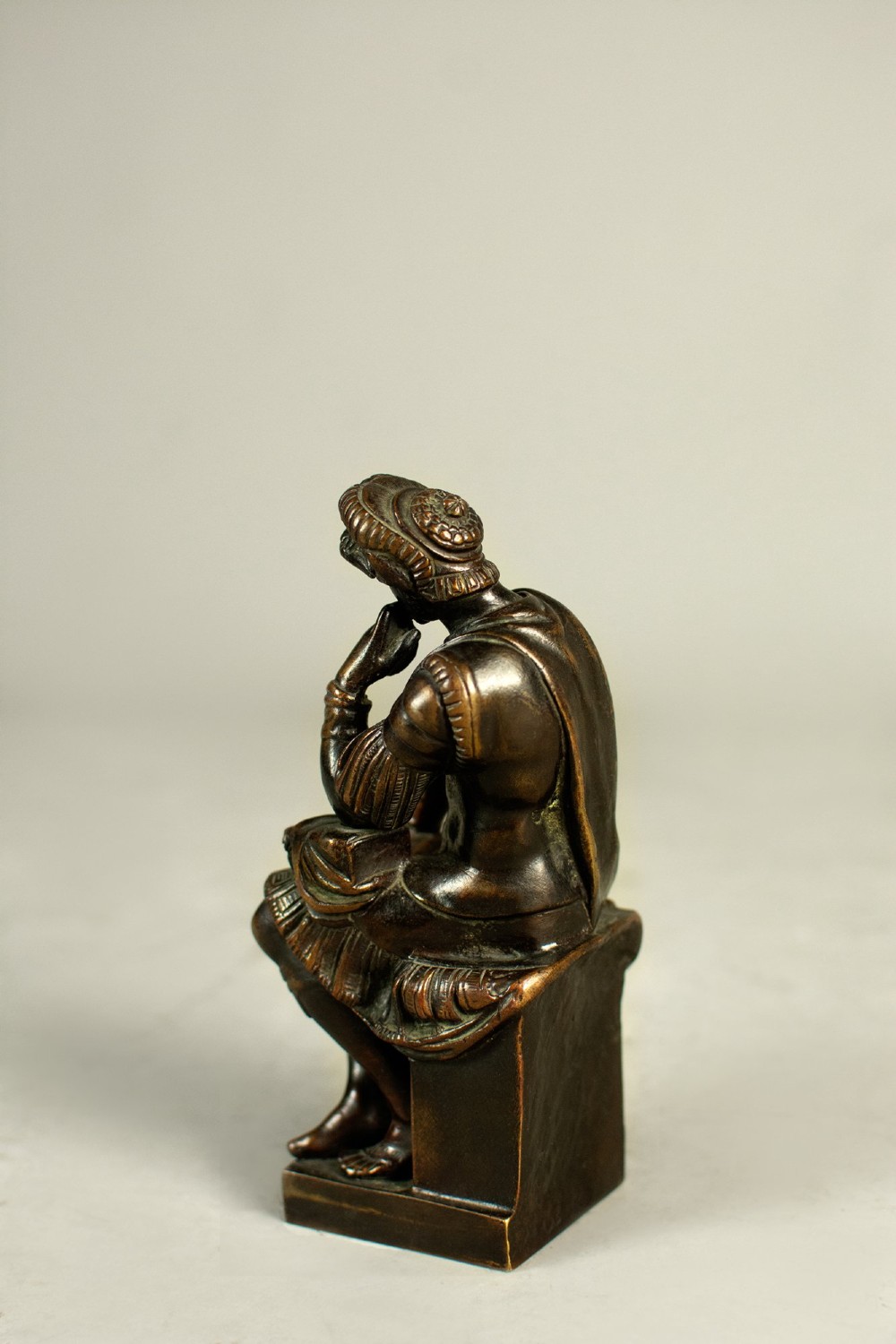 A dark patinated bronze figure depicting Lorenzo de Medici seated in a thoughtful pose on a rectangular base. View IV