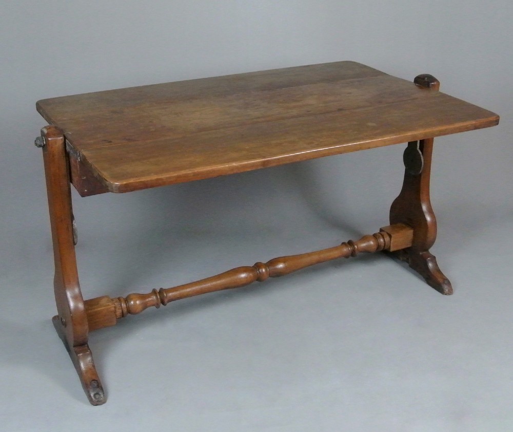 An 18th-century Georgian solid teak campaign table featuring a tilting rectangular top, a turned cross stretcher, and trestle end supports.