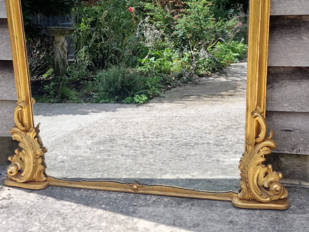 A large 19th-century giltwood mirror featuring carved C-scroll cresting, acanthus leaf detailing, and a gilded frame surrounding a glass plate. View IV