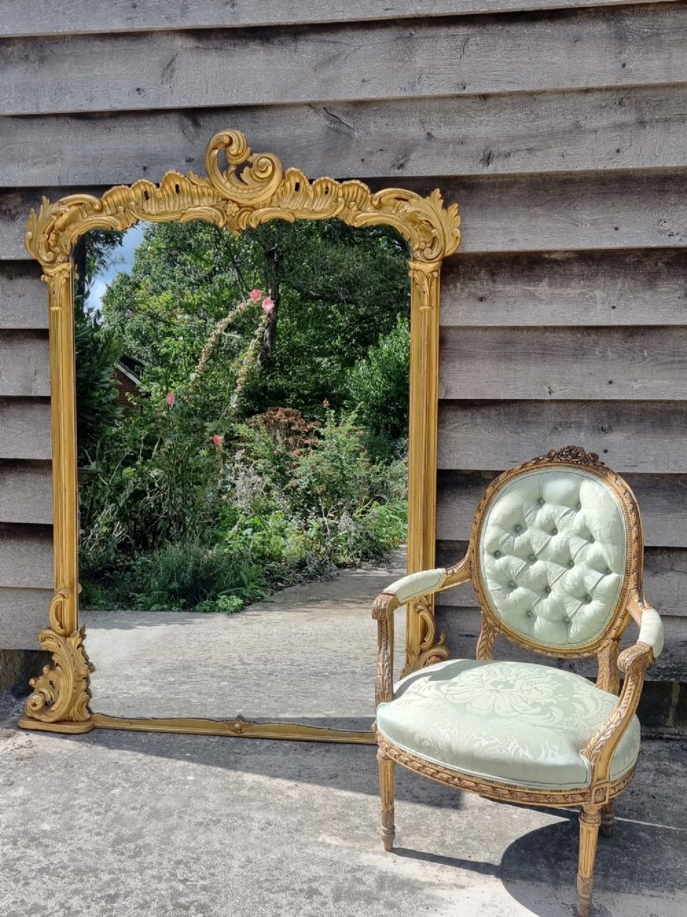 A large 19th-century giltwood mirror featuring carved C-scroll cresting, acanthus leaf detailing, and a gilded frame surrounding a glass plate. View V