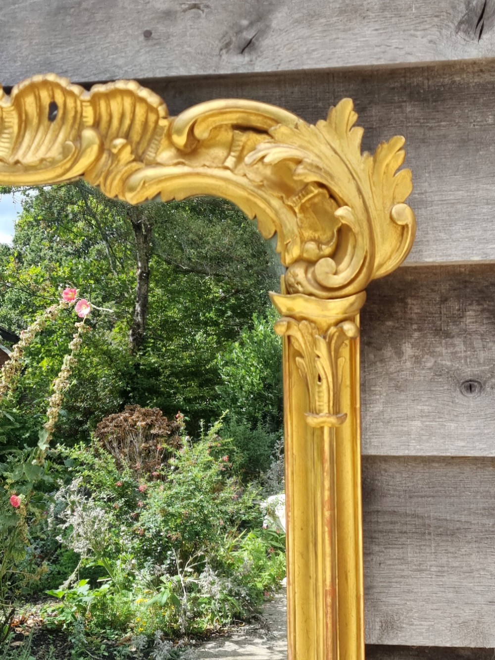 A large 19th-century giltwood mirror featuring carved C-scroll cresting, acanthus leaf detailing, and a gilded frame surrounding a glass plate. View VII