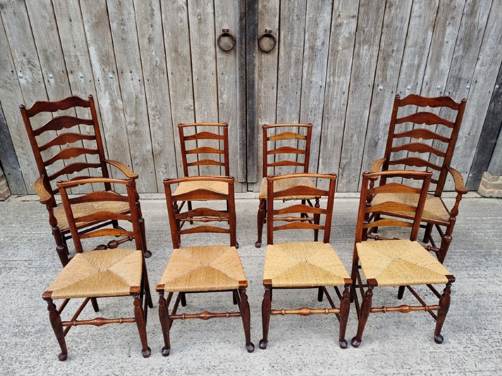 A set of eight 19th-century wooden country dining chairs featuring woven rush seats with green seat pads, shaped horizontal back slats, and turned legs. View VI