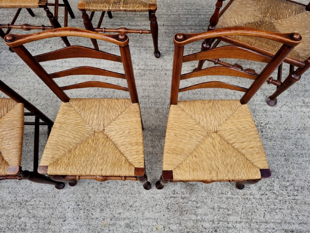 A set of eight 19th-century wooden country dining chairs featuring woven rush seats with green seat pads, shaped horizontal back slats, and turned legs. View VII