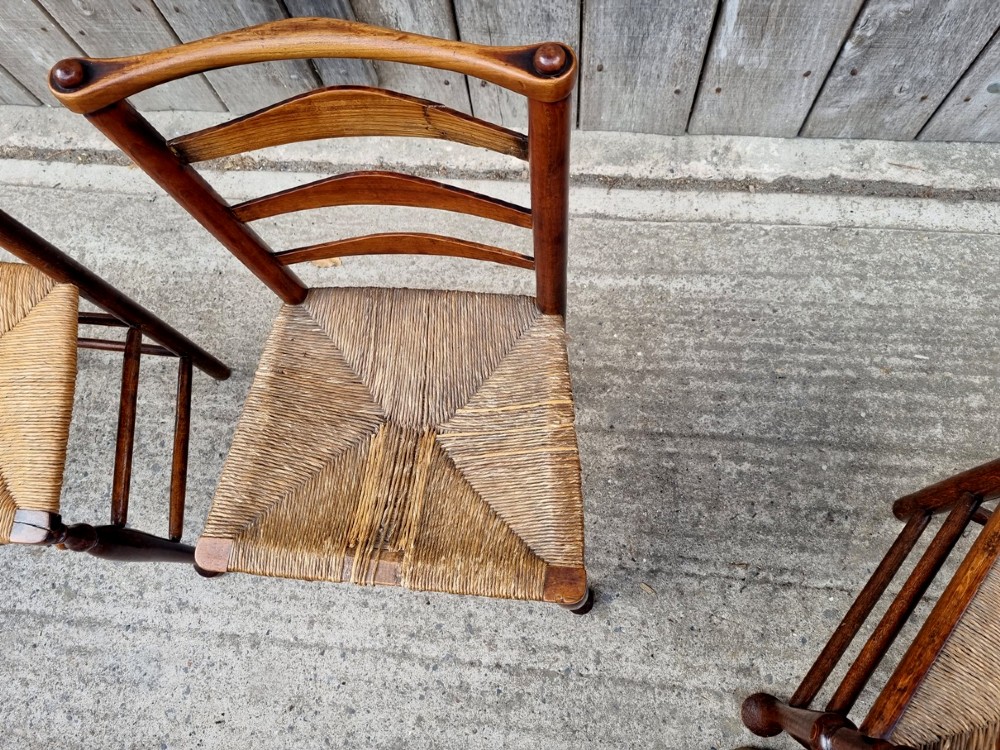 A set of eight 19th-century wooden country dining chairs featuring woven rush seats with green seat pads, shaped horizontal back slats, and turned legs. View VIII