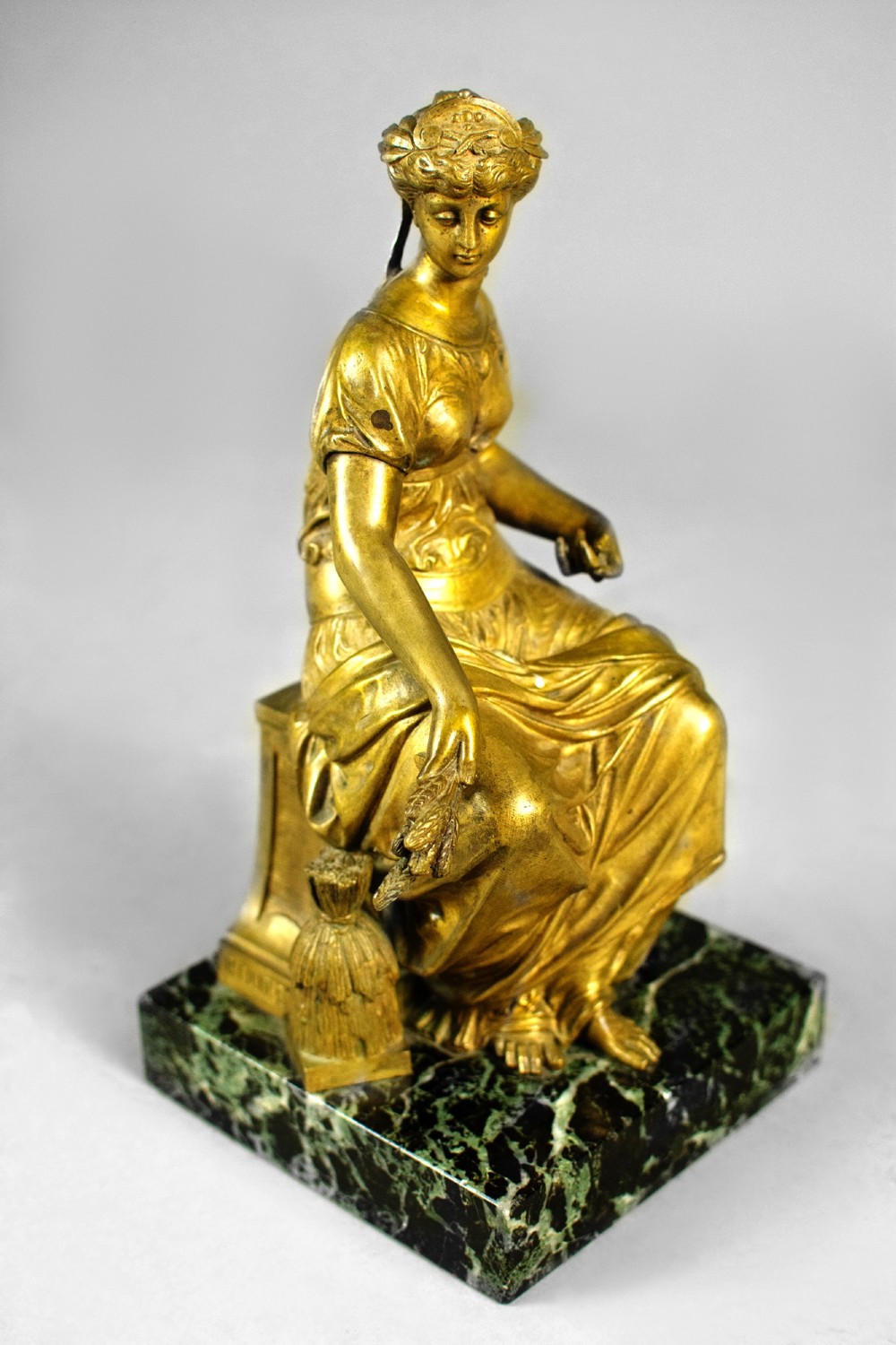 A nineteenth-century gilt bronze sculpture depicting the seated Roman goddess Ceres holding a sheaf of wheat on a square green marble base. View IV