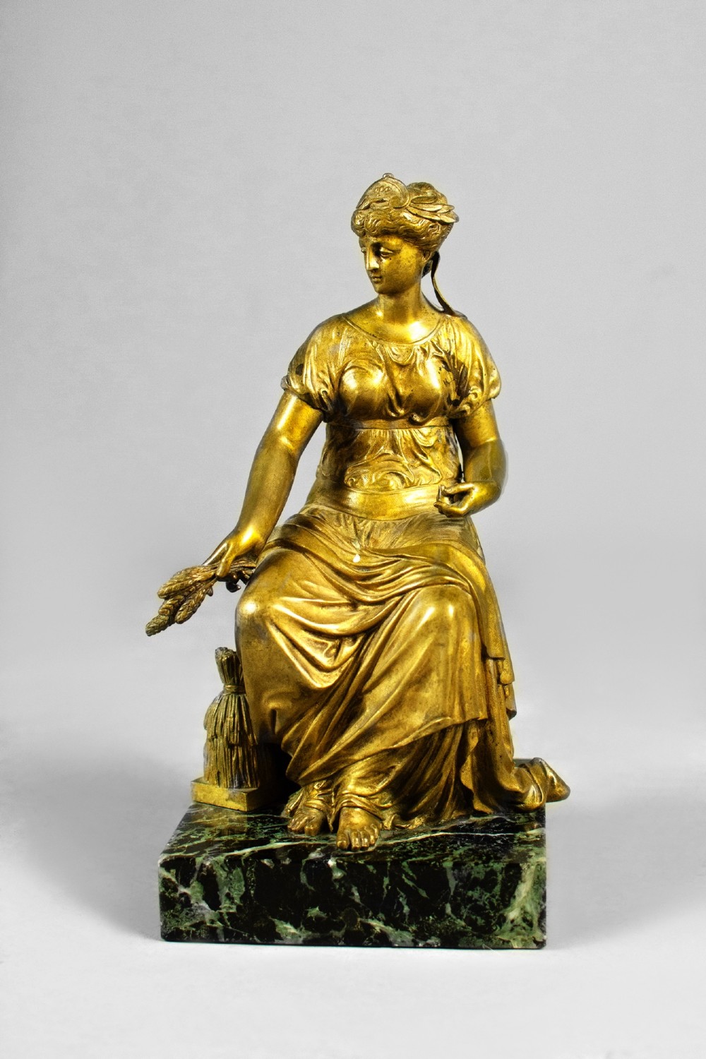 A nineteenth-century gilt bronze sculpture depicting the seated Roman goddess Ceres holding a sheaf of wheat on a square green marble base. View VIII
