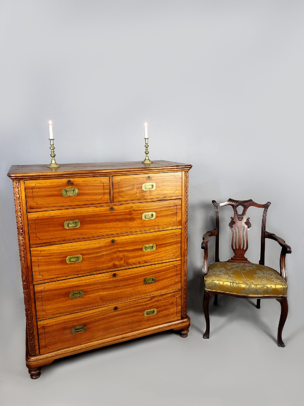 A nineteenth-century teak campaign chest of drawers featuring flush brass handles, keyholes, two short over three long drawers, and carved side pilasters. View III