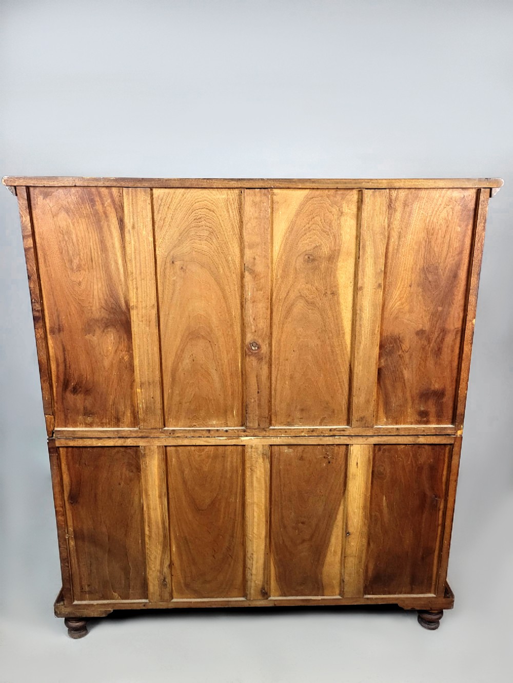 A nineteenth-century teak campaign chest of drawers featuring flush brass handles, keyholes, two short over three long drawers, and carved side pilasters. View IX