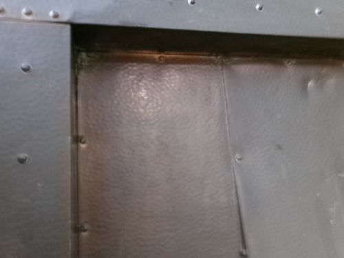 An Arts and Crafts patinated copper firefront featuring a central flared hood canopy and riveted border panels. View III