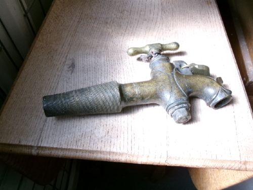 A heavy Victorian brass barrel tap featuring a tapered shaft, curved spout, T-bar handle, and an integrated locking loop mechanism. View III