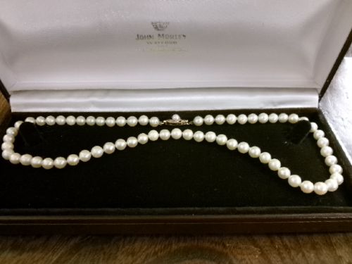 A single strand of white cultured pearls with a 9ct gold clasp displayed inside a dark brown presentation case. View IX