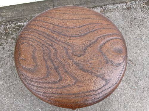 An antique Victorian wooden tavern stool featuring a circular thick elm seat and turned splayed legs joined by stretchers. View VIII
