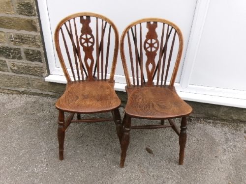 A pair of traditional wooden Windsor chairs featuring contoured elm seats, pierced wheelback splats, hoop backs, and turned legs connected by H-stretchers. View VII