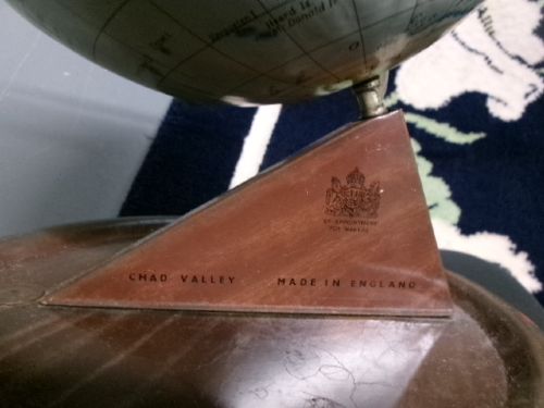 A vintage tinplate world globe with a pale blue lithographed ocean map mounted on a circular metal base with a curved semi-meridian arm. View V