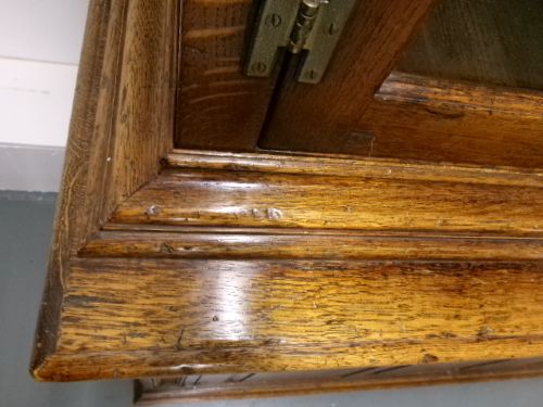 A large two-section warm brown oak bookcase featuring two upper glazed doors with internal shelves above two lower field-panelled wooden doors. View XII