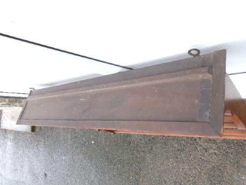 A mahogany wall-hanging rack featuring a top shelf, open tiers with horizontal retaining bars, shaped side brackets, and top brass mounting rings. View III