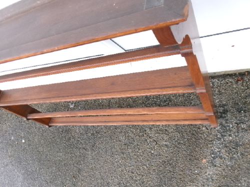 A mahogany wall-hanging rack featuring a top shelf, open tiers with horizontal retaining bars, shaped side brackets, and top brass mounting rings. View IV