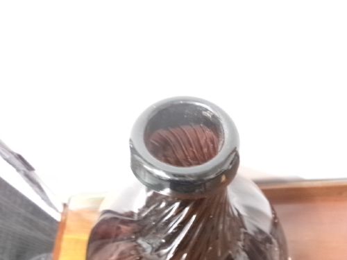 A deep amethyst hand-blown glass bottle featuring a bulbous onion-shaped body, a spiral-ribbed tapering neck, and an applied string lip rim. View IV