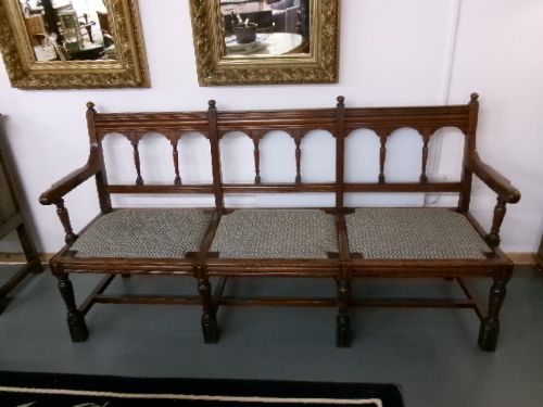 A late Victorian carved walnut three-seater bench featuring an arched spindle backrest, armrests, upholstered seat pads, and turned front legs. View III