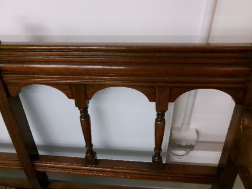 A late Victorian carved walnut three-seater bench featuring an arched spindle backrest, armrests, upholstered seat pads, and turned front legs. View VI