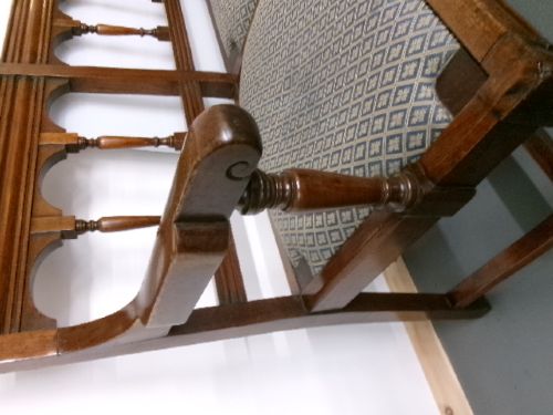 A late Victorian carved walnut three-seater bench featuring an arched spindle backrest, armrests, upholstered seat pads, and turned front legs. View XIV