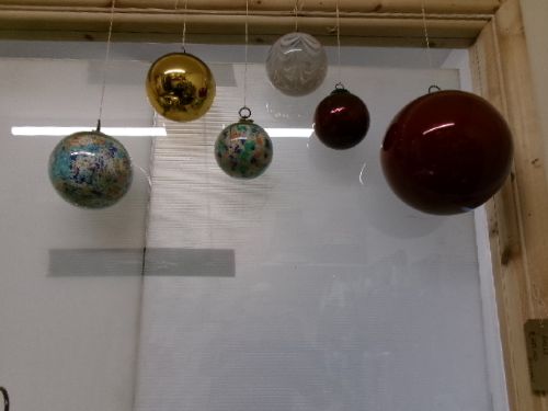 A collection of six assorted antique Victorian hand-blown glass witch balls in gold, red, and speckled colourways suspended by string. View II