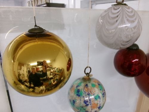 A collection of six assorted antique Victorian hand-blown glass witch balls in gold, red, and speckled colourways suspended by string. View V