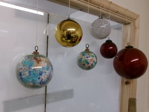A collection of six assorted antique Victorian hand-blown glass witch balls in gold, red, and speckled colourways suspended by string. View X