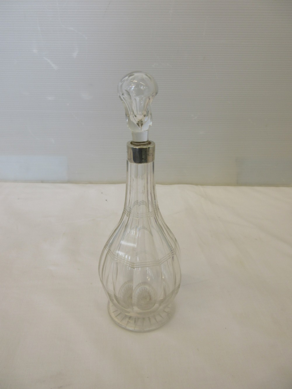 A clear cut-glass oil bottle featuring a sterling silver collar and a matching glass stopper.