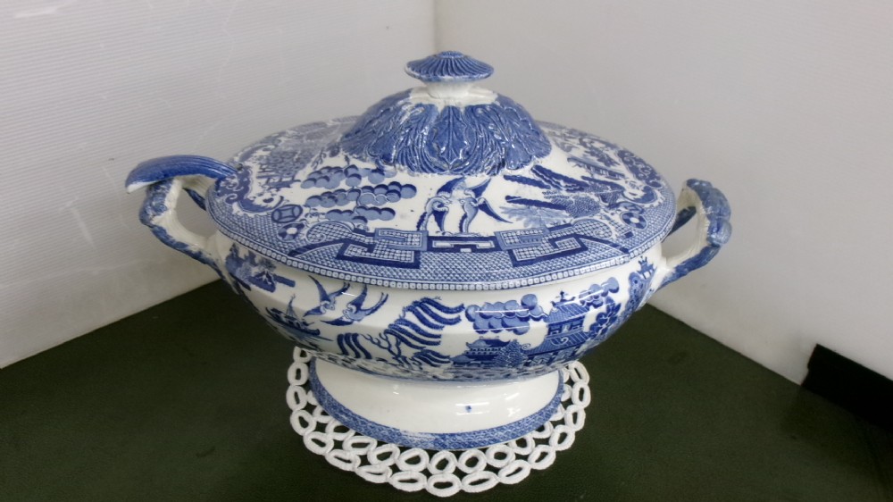 An antique blue and white transferware lidded soup tureen with matching ladle featuring traditional Willow pattern motifs.