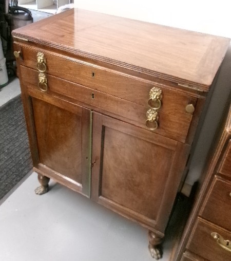 A Georgian mahogany writing desk featuring lion mask brass drawer handles, a lower double door cabinet, and detailed brass paw feet.