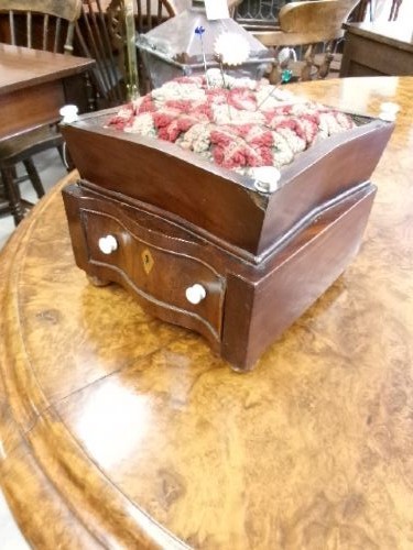 A 19th-century square mahogany pincushion featuring a padded fabric top above a small wooden drawer with two white knobs and bun feet. View IX