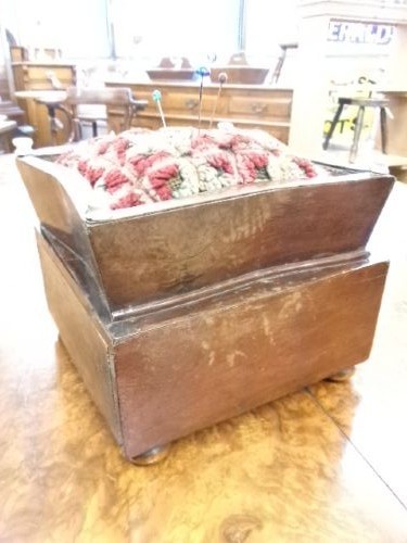 A 19th-century square mahogany pincushion featuring a padded fabric top above a small wooden drawer with two white knobs and bun feet. View VII